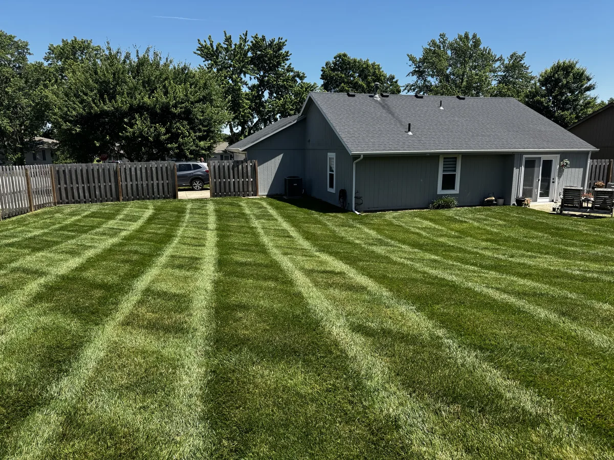 Backyard lawn with crisp diagonal mowing stripes maintained by B&B Lawn & Landscape in Lee's Summit Missouri