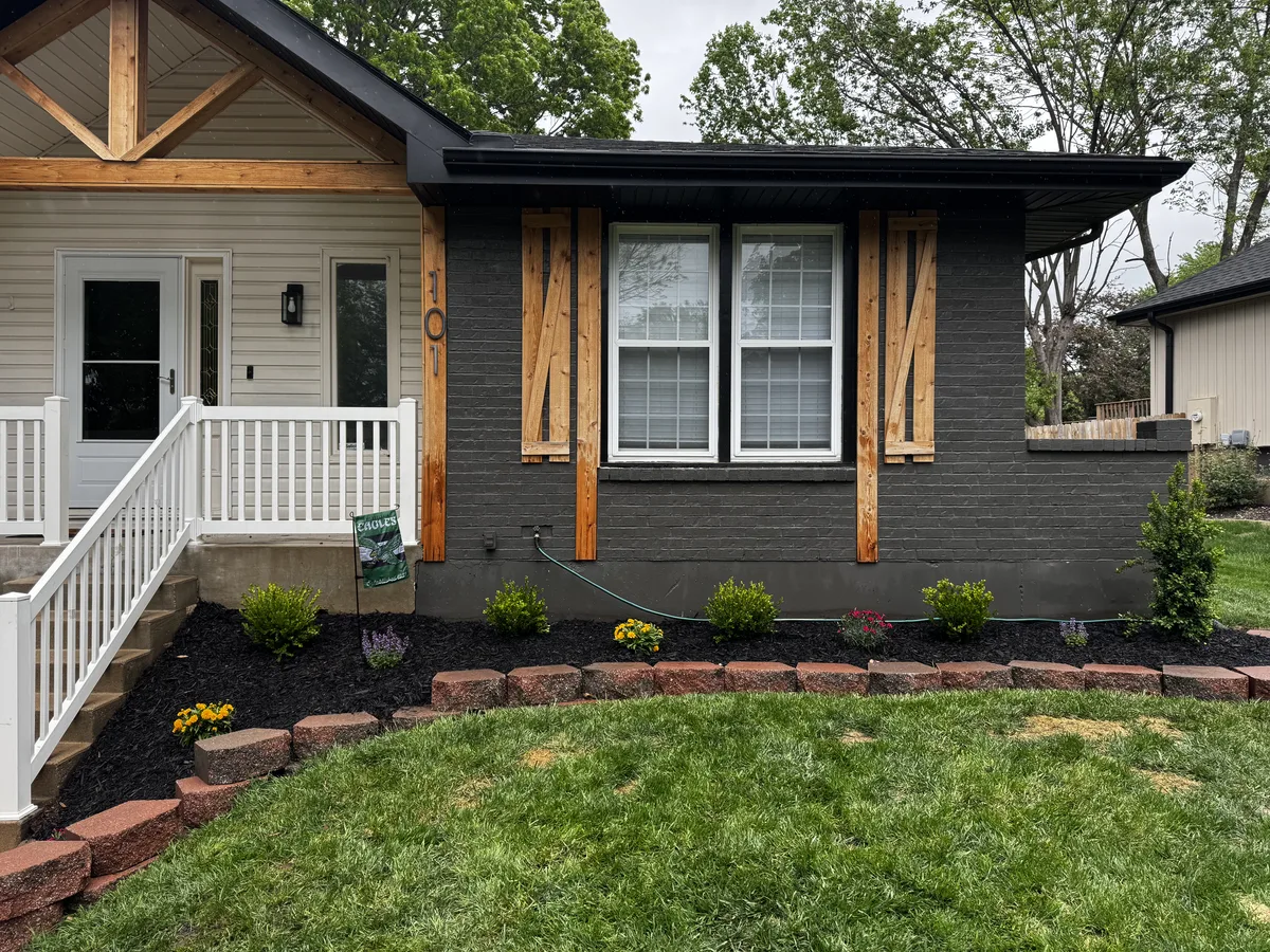 Fresh black mulch flower beds with stone edging along a home's front landscaping by B&B Lawn & Landscape